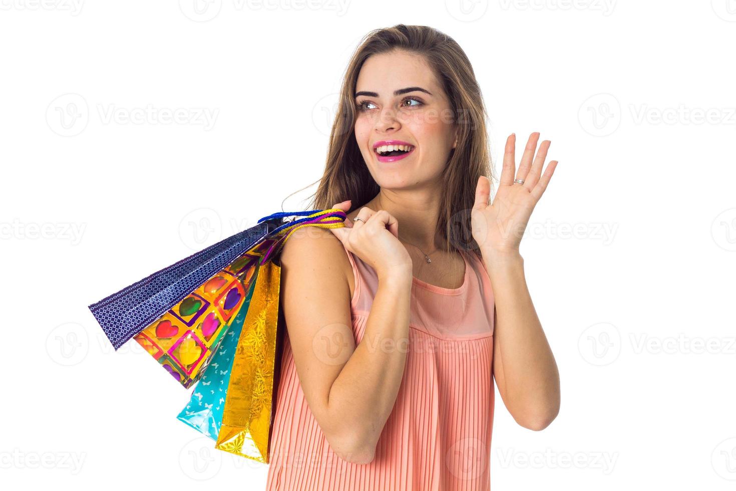 la joven se ríe y mira hacia la celebración de bolsas de colores aisladas en el fondo blanco foto