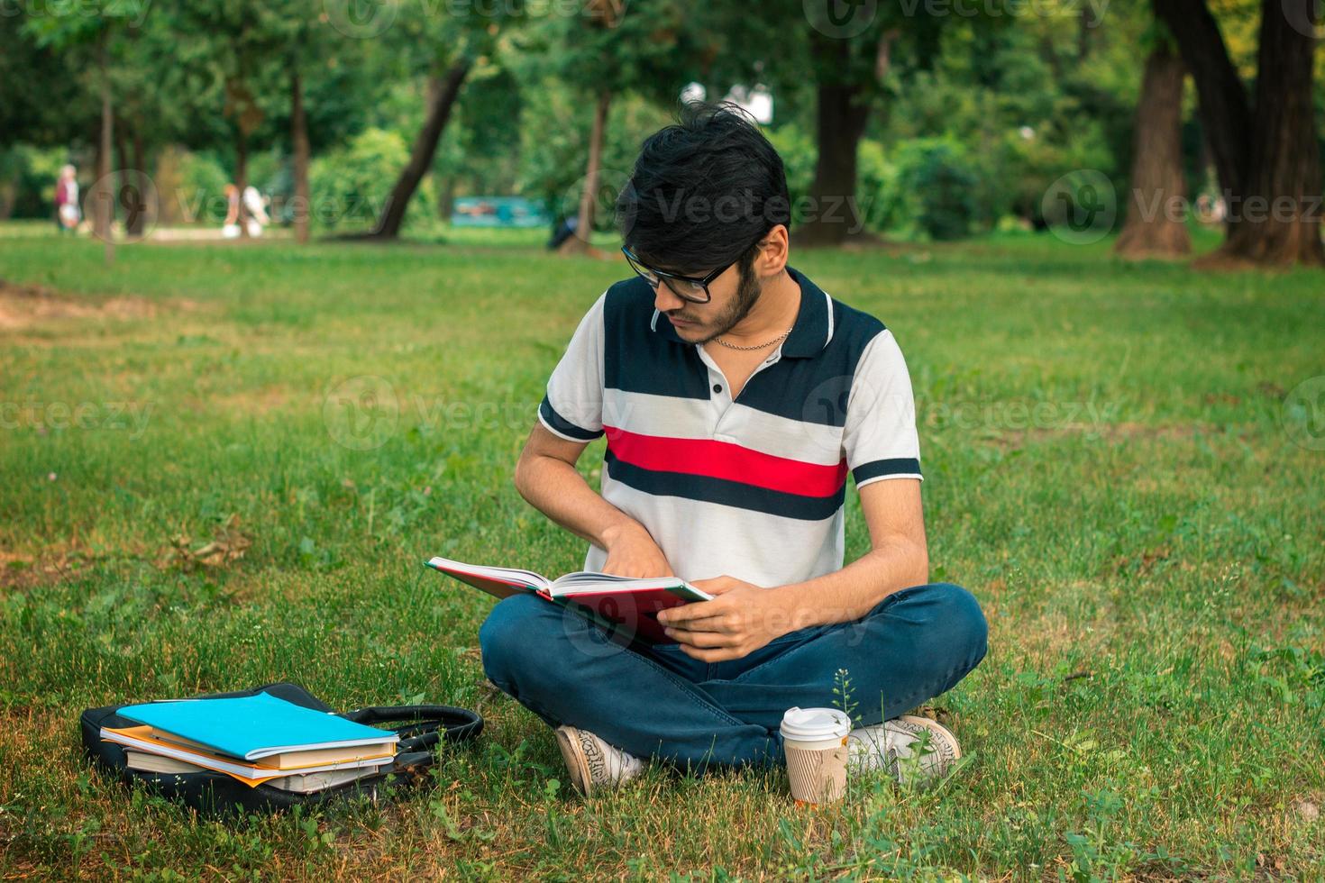 brunette student man reading books on a  grass photo