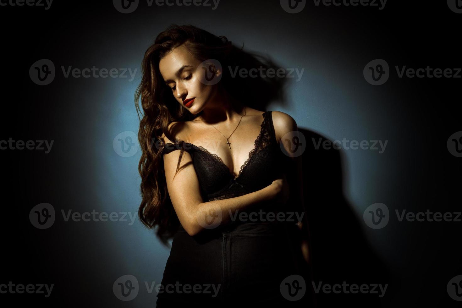 Gorgeous lady with curly hairstyle in dark studio photo