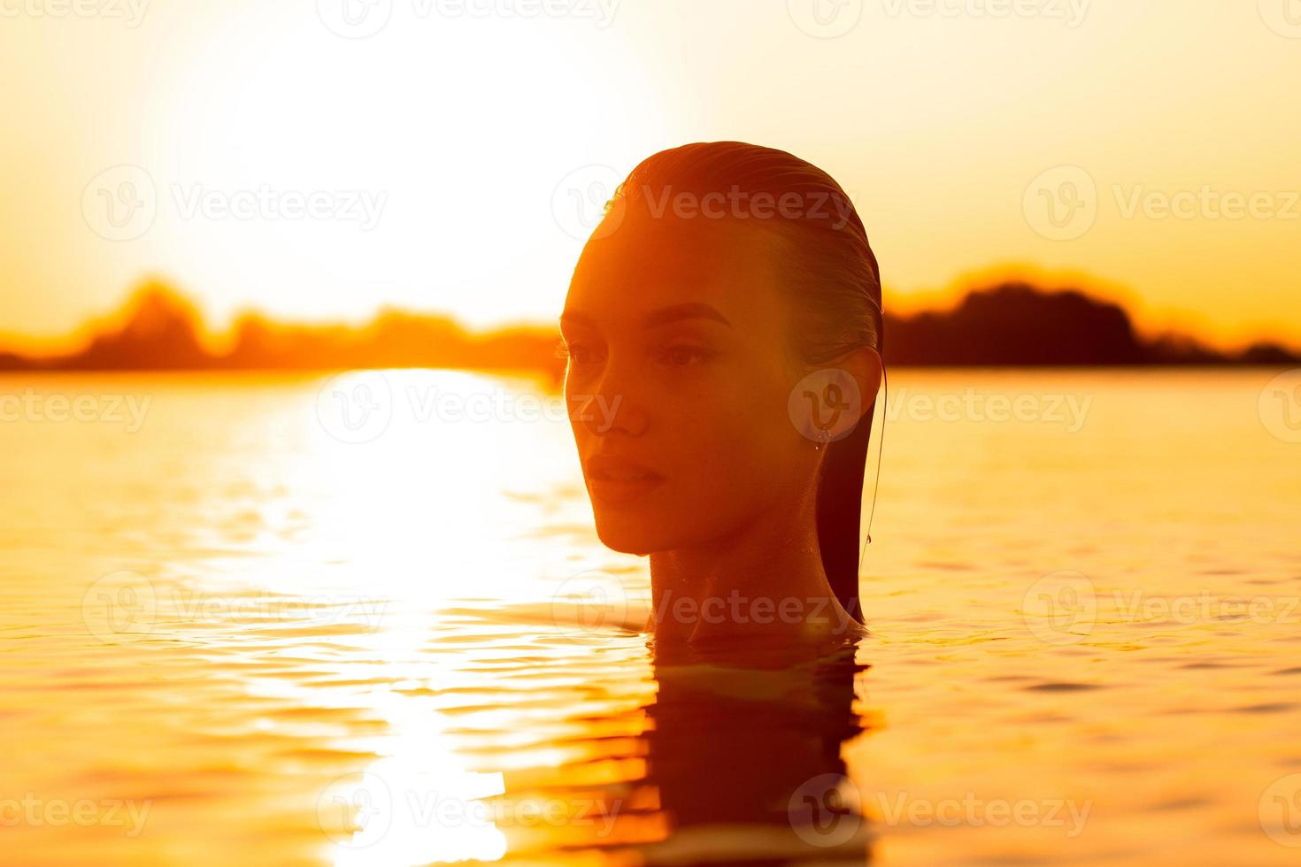 Sexual young lady in the sea at warm sunset photo
