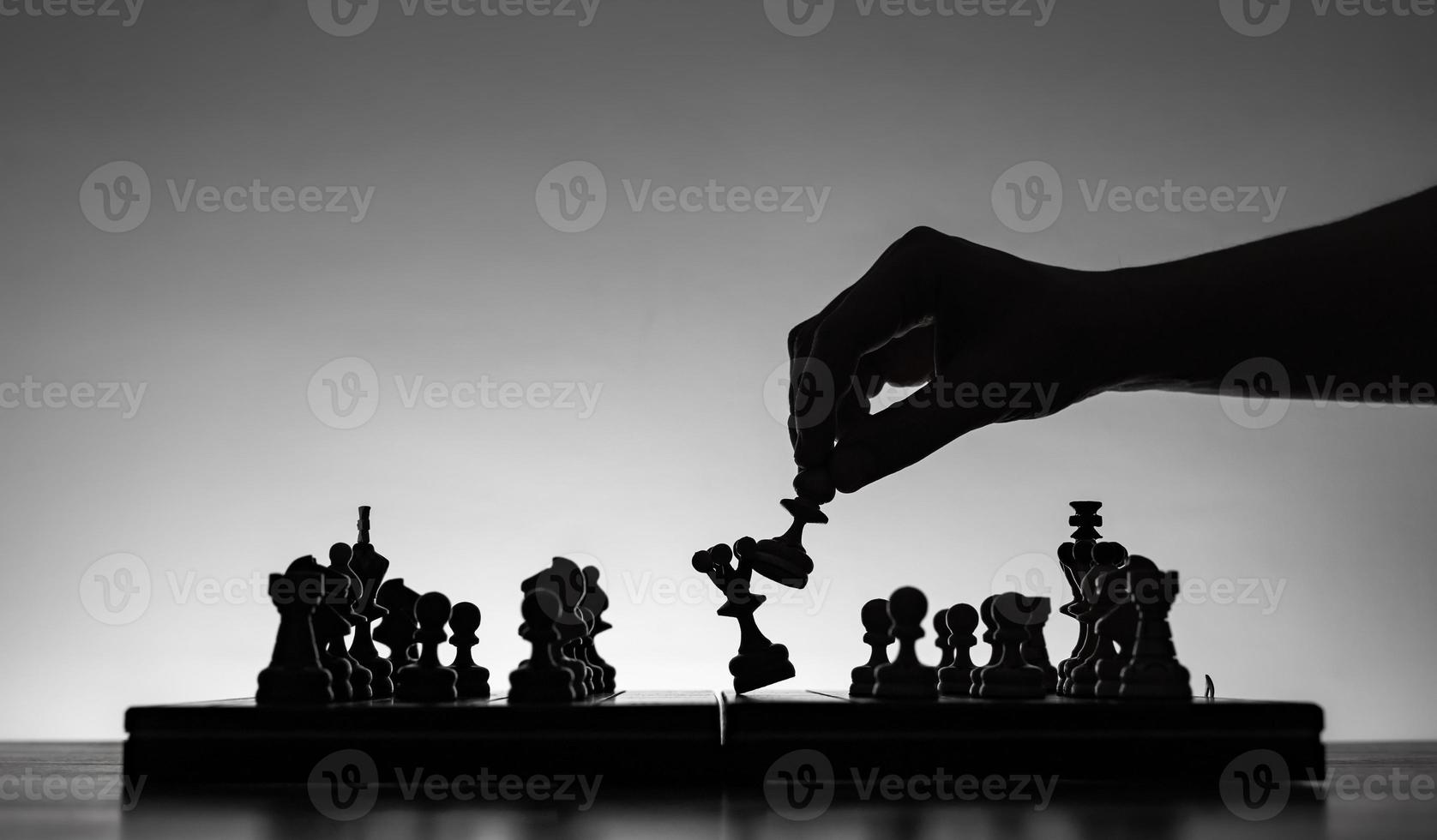 Chess board with chess pieces silhuettes on white background. Concept of business ideas and competition and strategy ideas. Black and White classic art photo. Beating the queen. photo