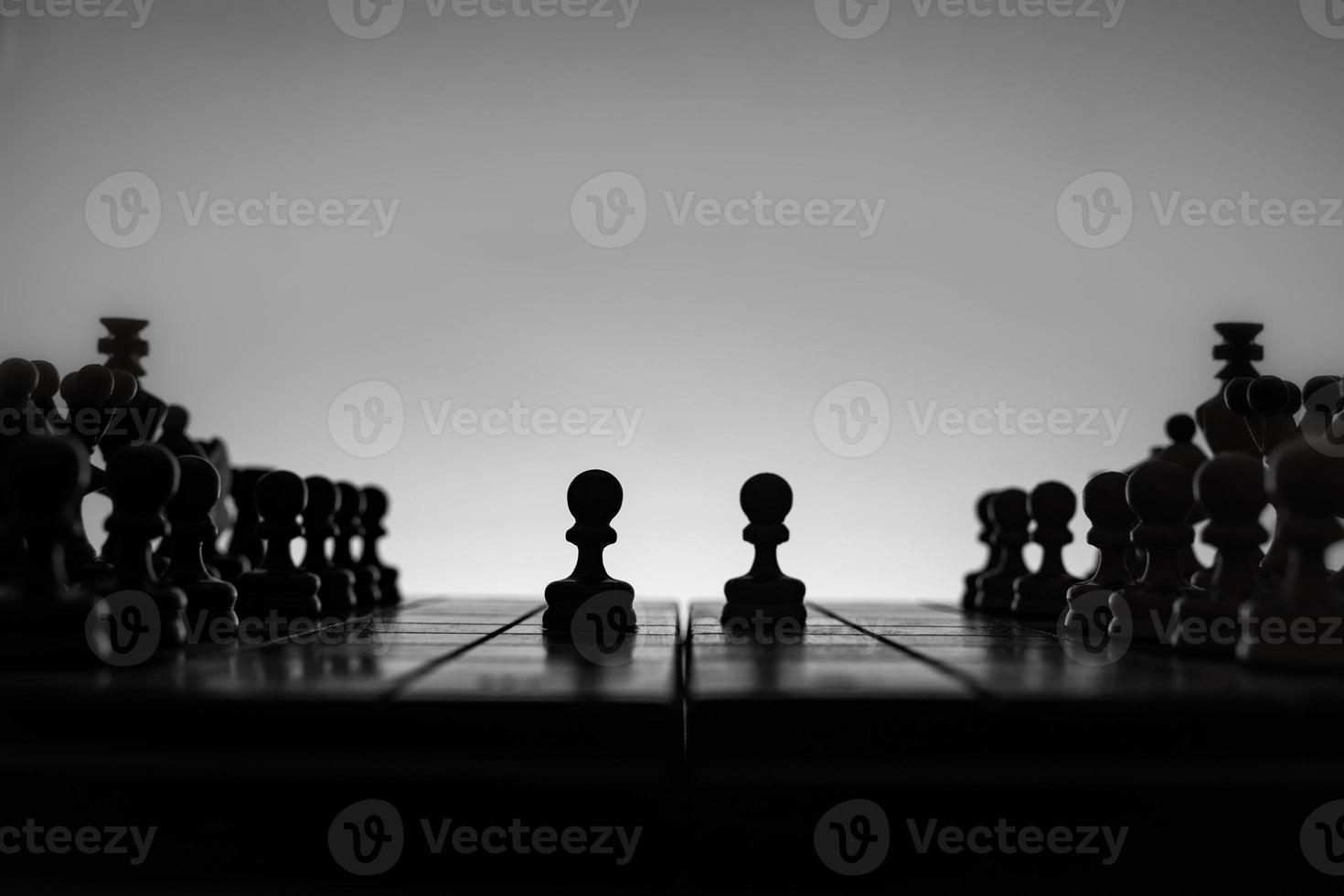 Chess board with chess pieces silhuettes on white background. Concept of business ideas, competition and strategy ideas. Black and White art photo. Popular king's pawn opening and scandinavian defense photo