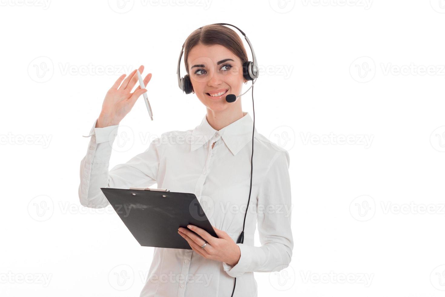 joven y alegre mujer de negocios con auriculares y micrófono mirando hacia otro lado y sonriendo aislada de fondo blanco foto