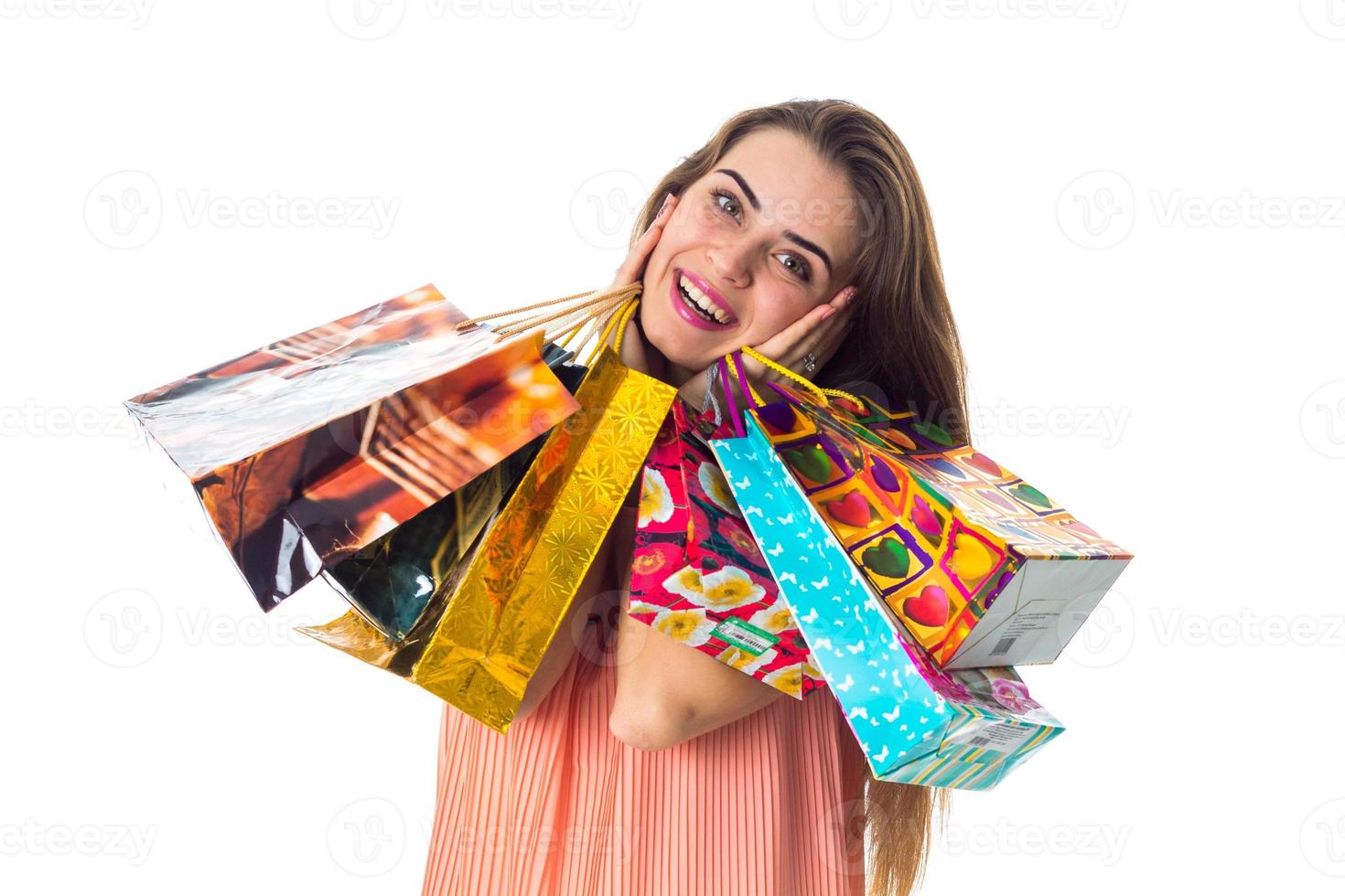 cute girl smiles and keeps near the face many great gift packages, isolated on white background photo