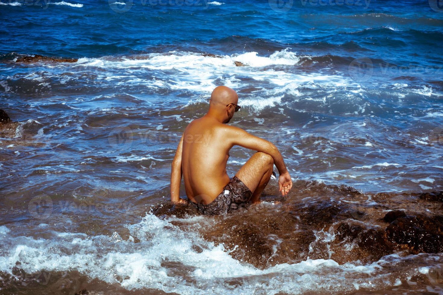 hombre guapo en la costa rocosa marina foto