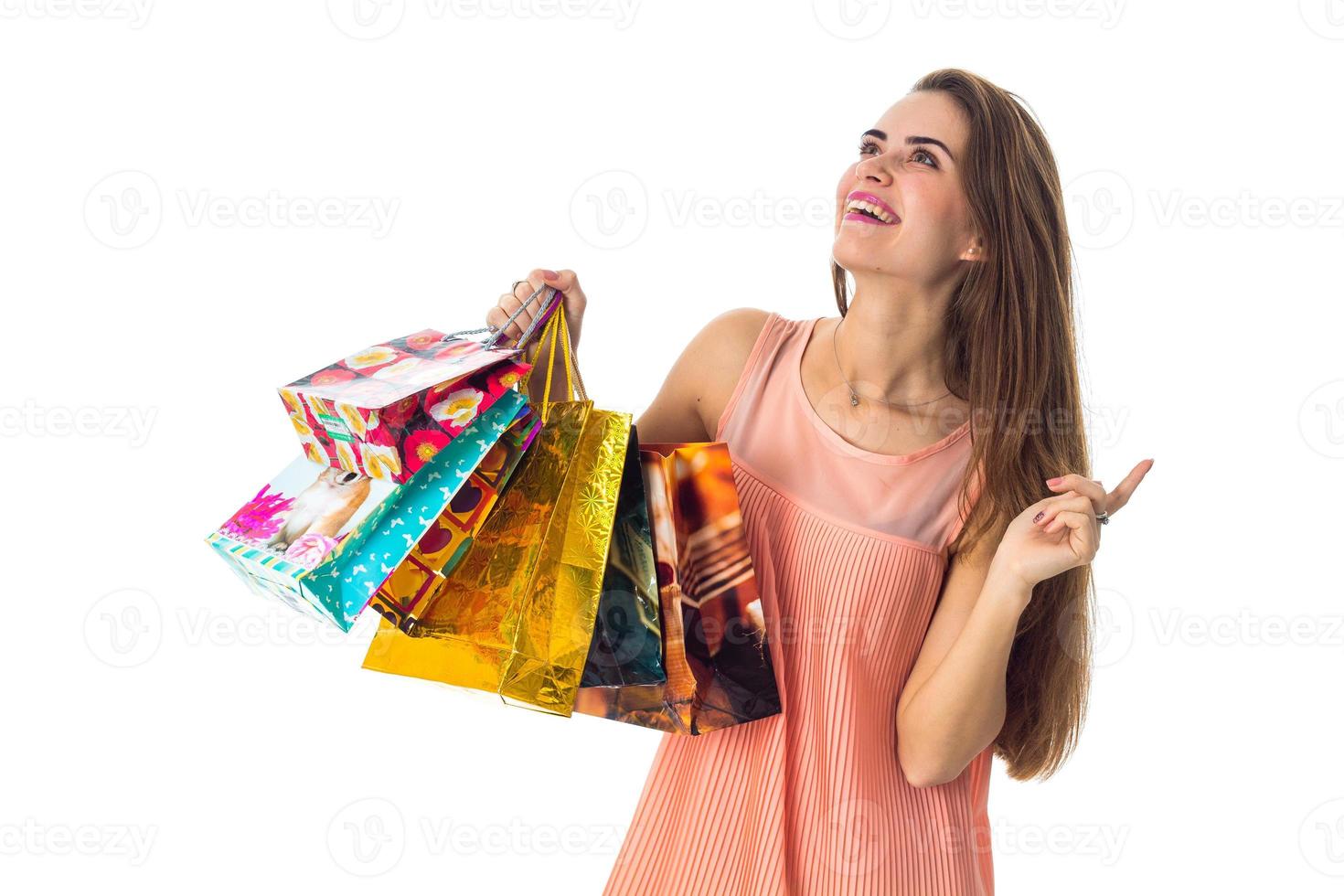 Merry girl looks up and holding a colorful shopping bags isolated on white background photo