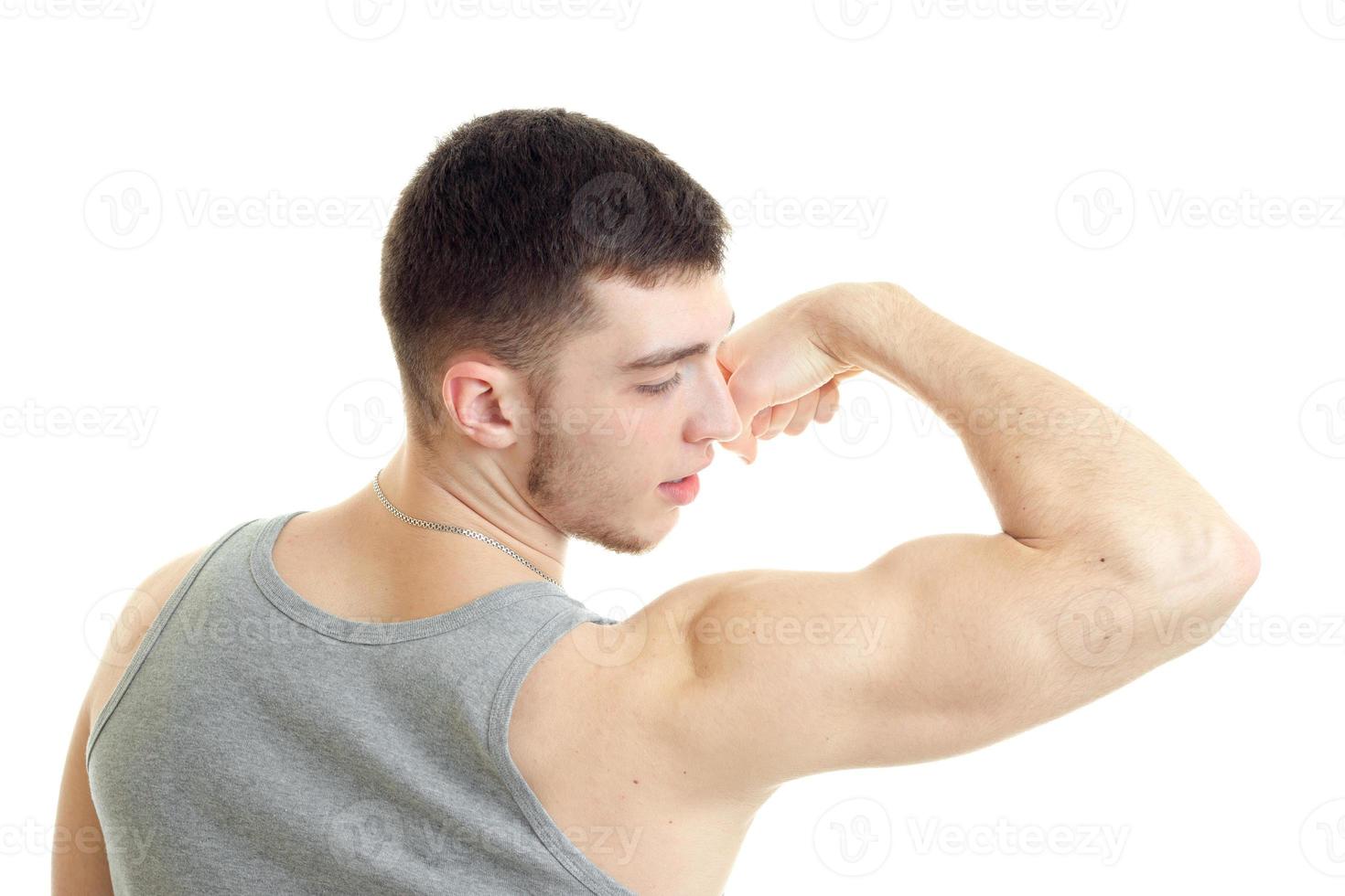 beautiful sporty guy stands with his back to the camera and strain on the arm muscles closeup photo