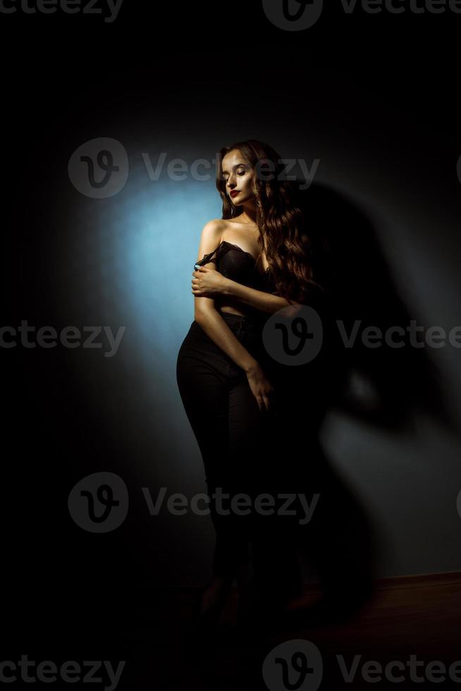 Gorgeous lady with curly hairstyle in dark studio photo