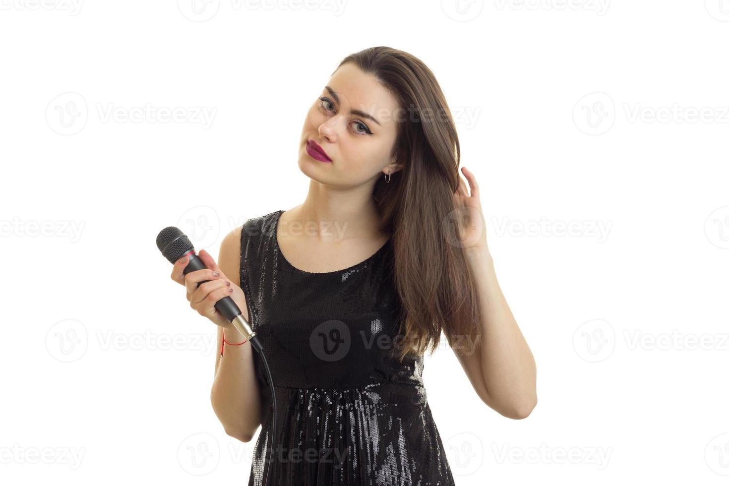 beautiful young girl in black shiny dress and a microphone in her hand photo