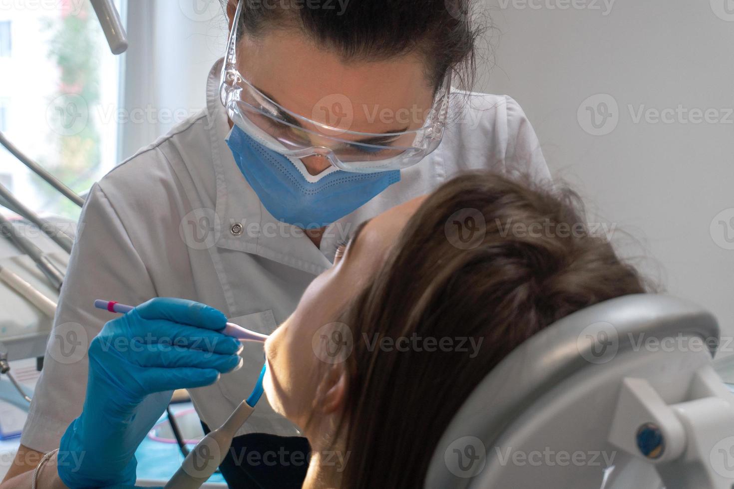 dentist treats teeth to a girl in a clinic photo