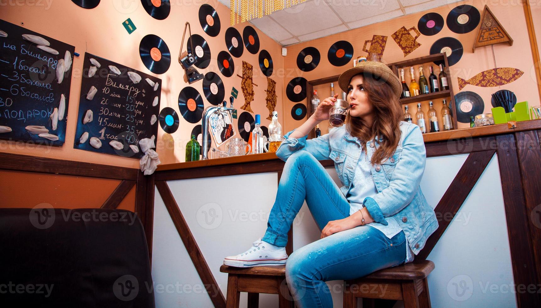 chica divertida y elegante en el bar bebiendo un cóctel a través de una pajita foto