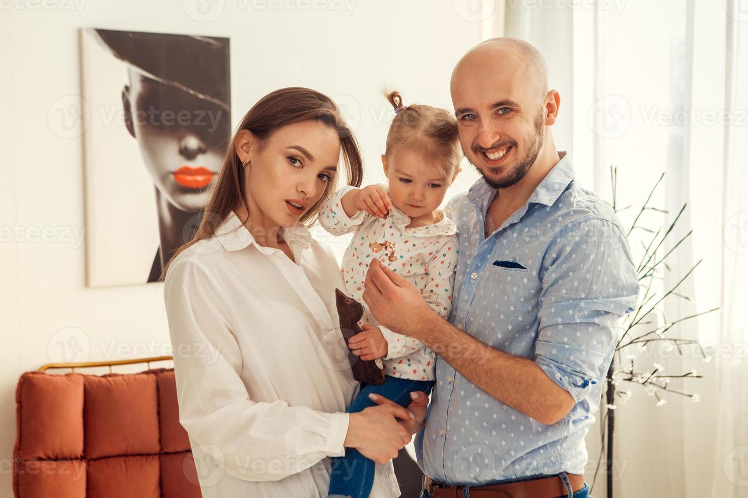 Mother father and little daughter posing on camera at home photo