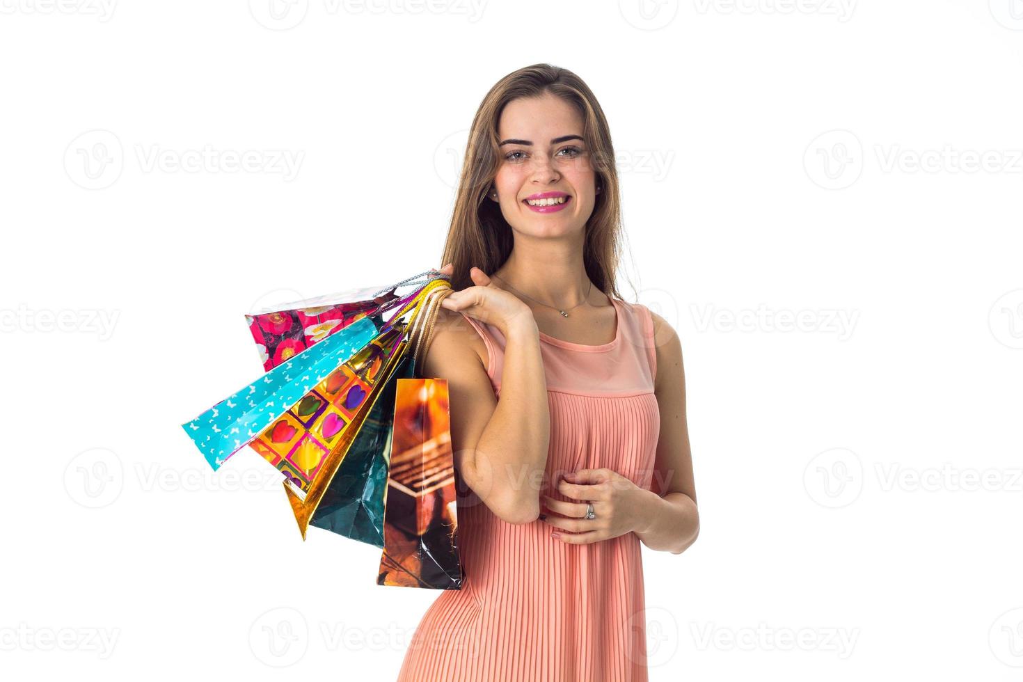 smiling young girl stands up straight looks ahead and holds in his hand the different packages with gifts is isolated on a white background photo