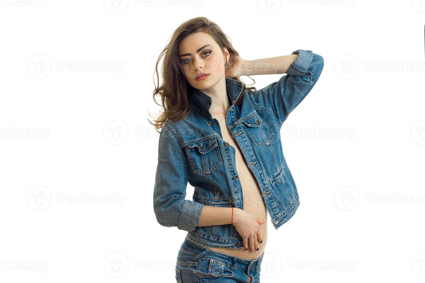 charming brunette in jeans clothes keeps the arm near the hair and looks into the distance photo