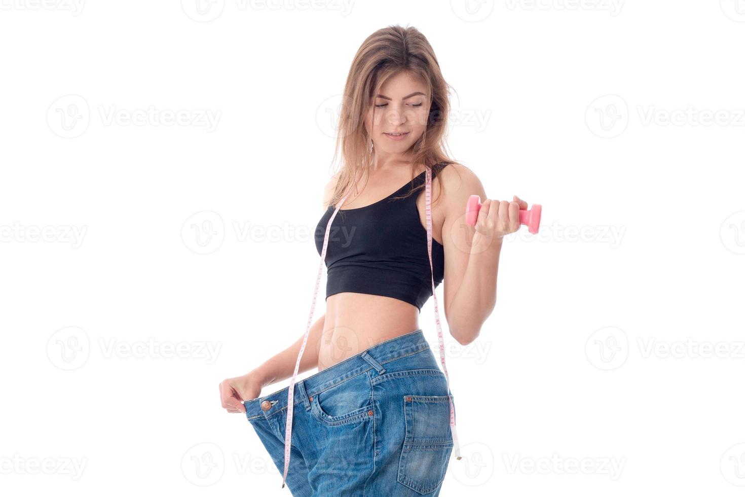 Fitness girl wore large pants and holding a dumbbell in your hand isolated on white background photo