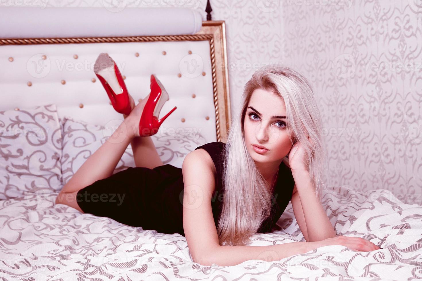 Horizontal portrait of beautiful blonde woman lying on bed photo