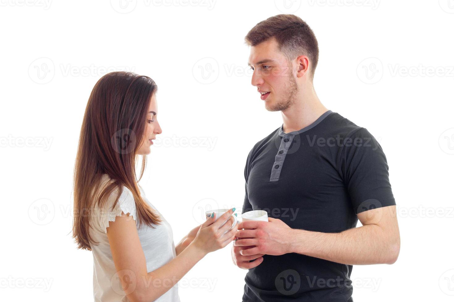 beautiful young guy with a girl look at each other and carrying cups of tea photo