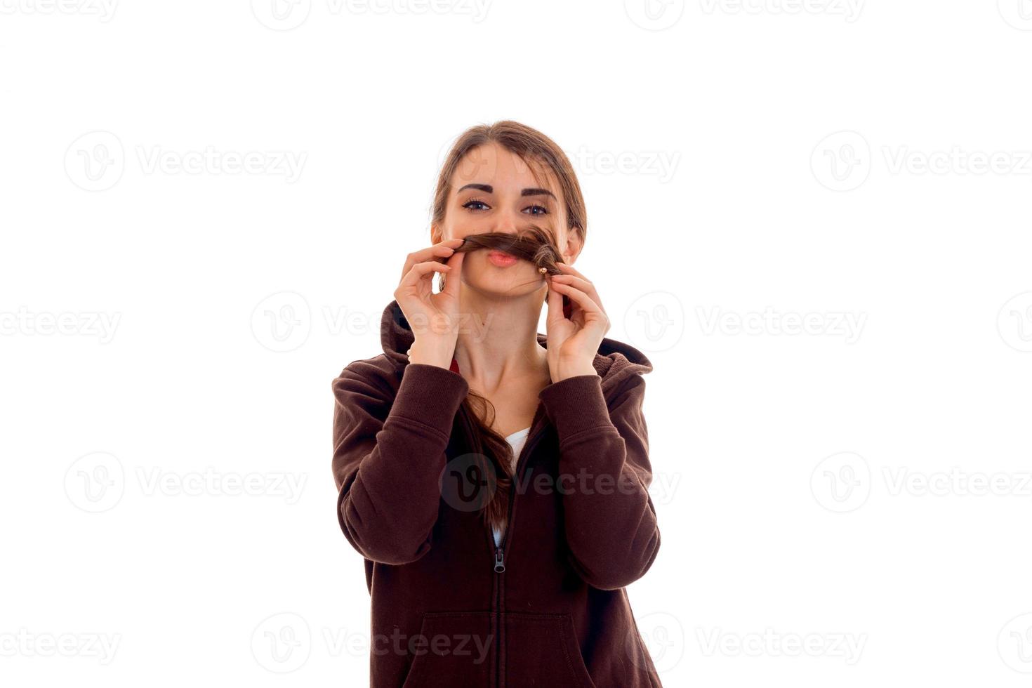 young funny girl in brown jacket keeps hands hair near the mouth photo