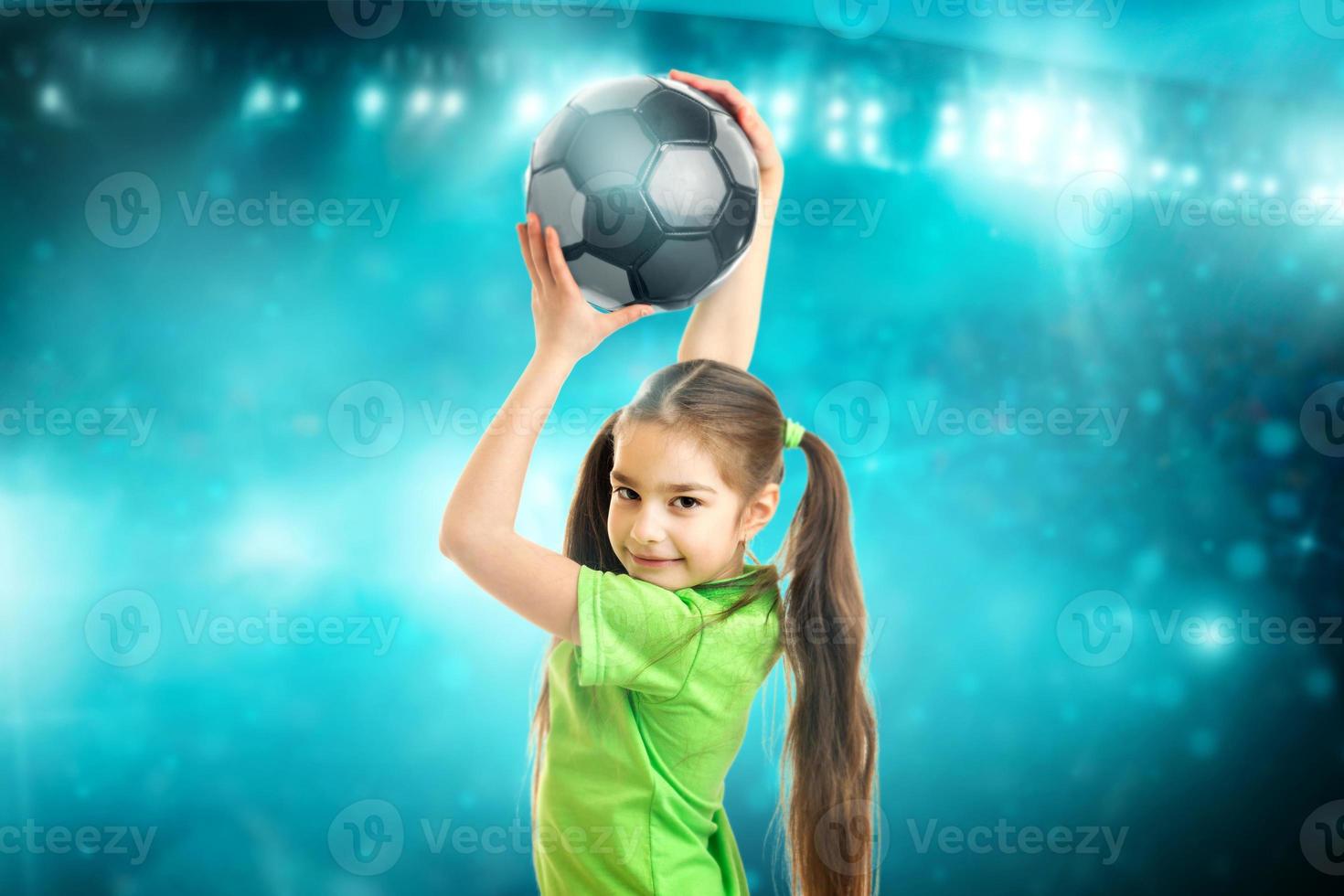 Portrait of a little girl smiles on camera with soccer ball in her hands photo