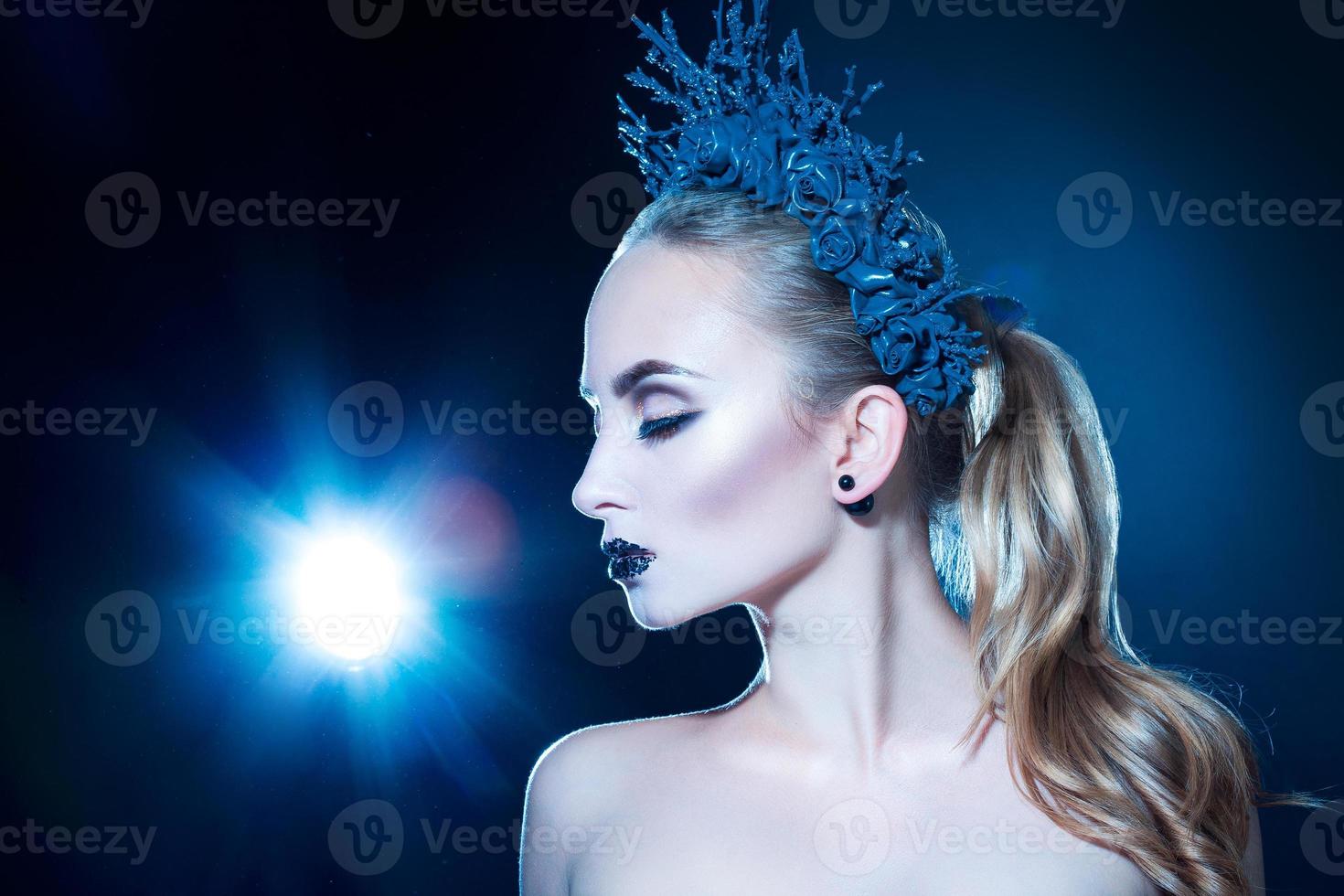 Pretty young girl with wreath on head and nice makeup on black background photo