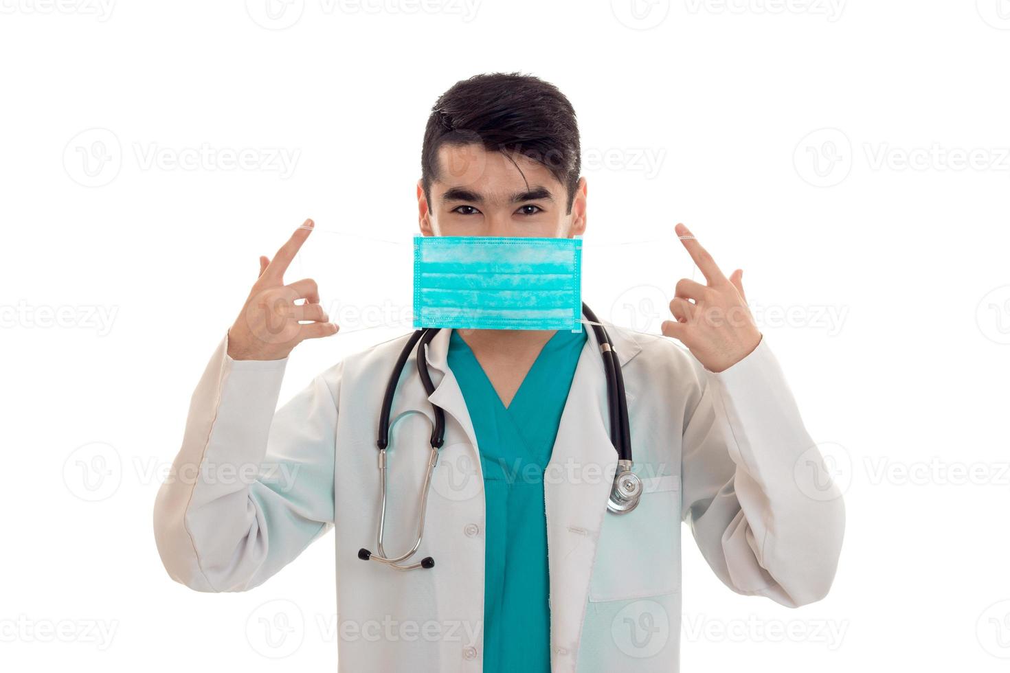 young beautiful doctor in blue uniform and mask with stethoscope on his neck isolated on white background photo