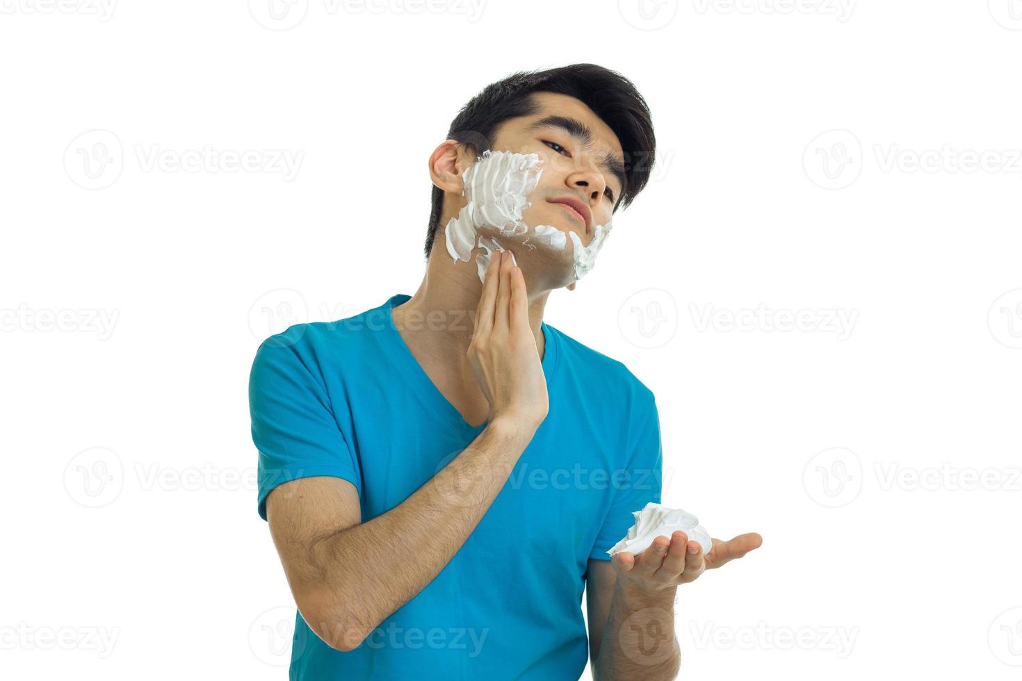 young handsome guy in the blue shirt tilted his head and putting a face shaving foam photo