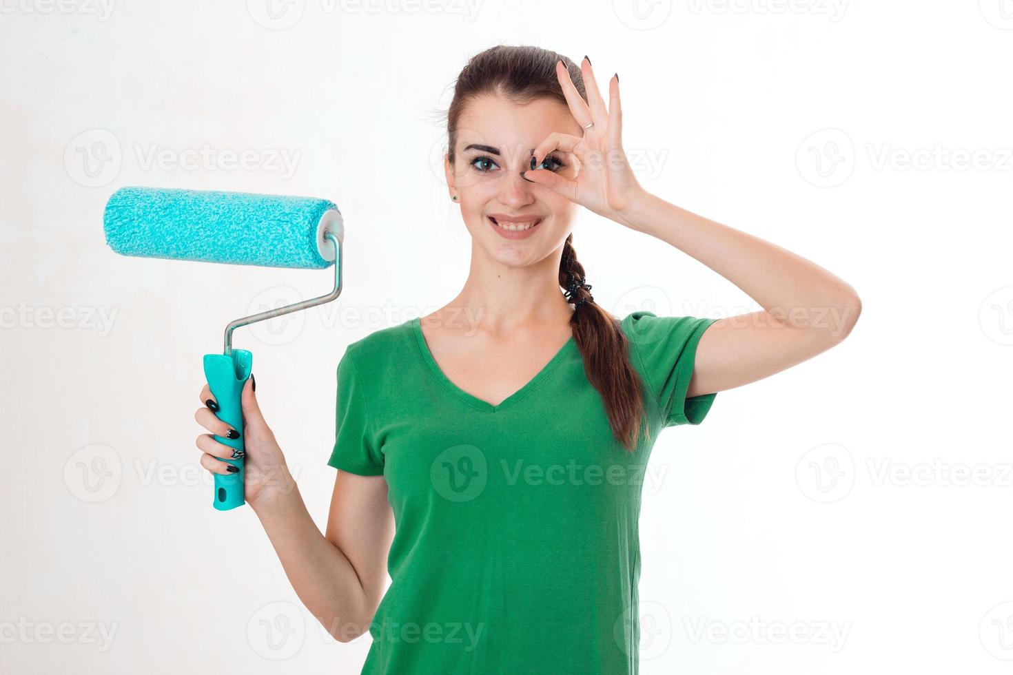 young happy brunette woman builder in uniform with paint roller in hands make reovations isolated on white background photo