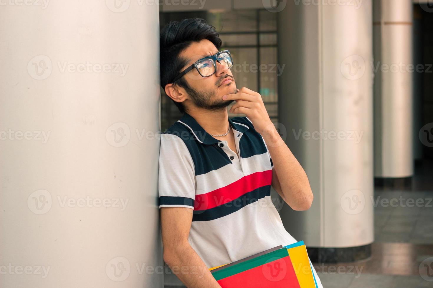 Nice thoughtful guy in glasses stands near the columns photo