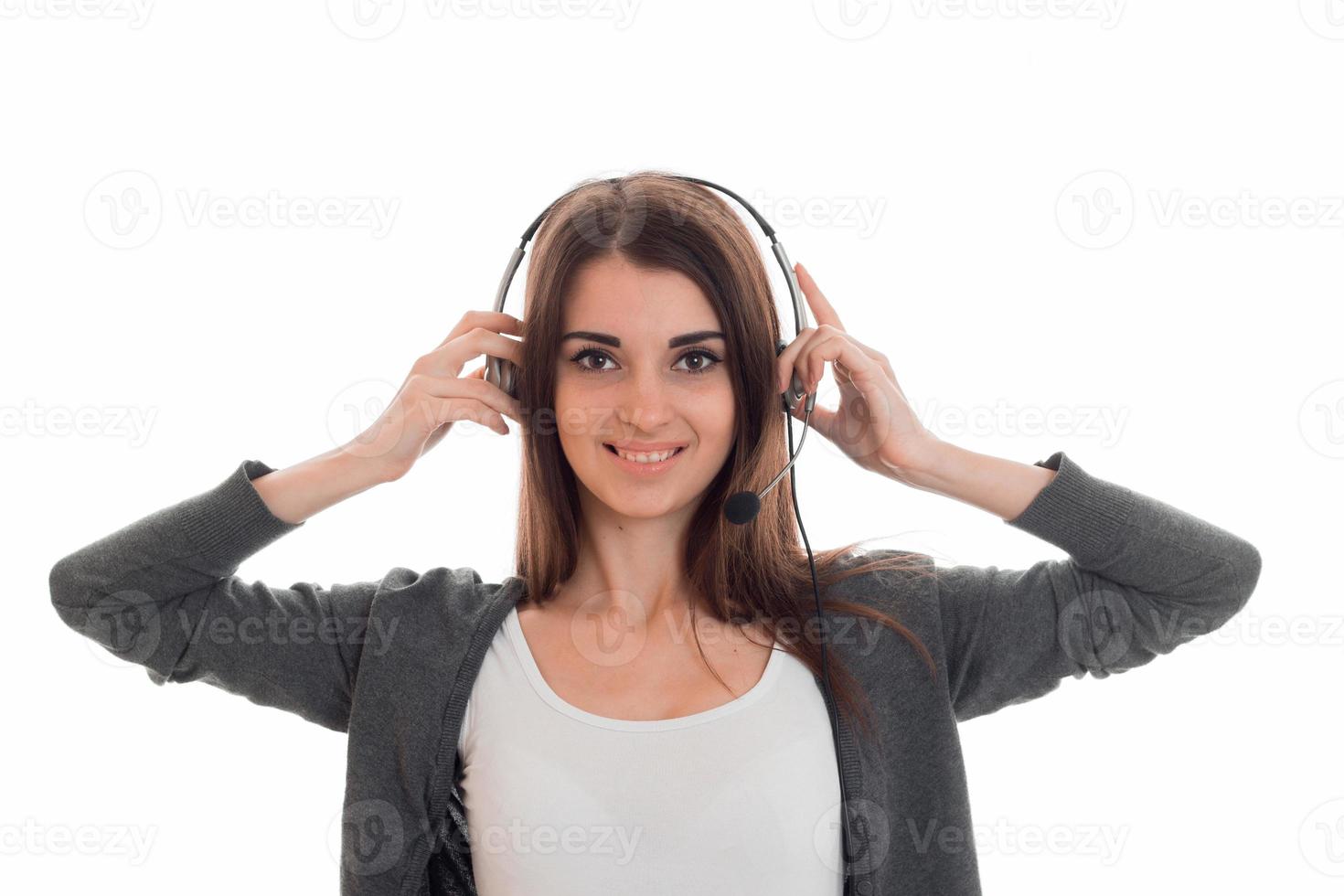 young charming brunette business woman with headphones and microphone looking at the camera and smiling isolated on white background photo