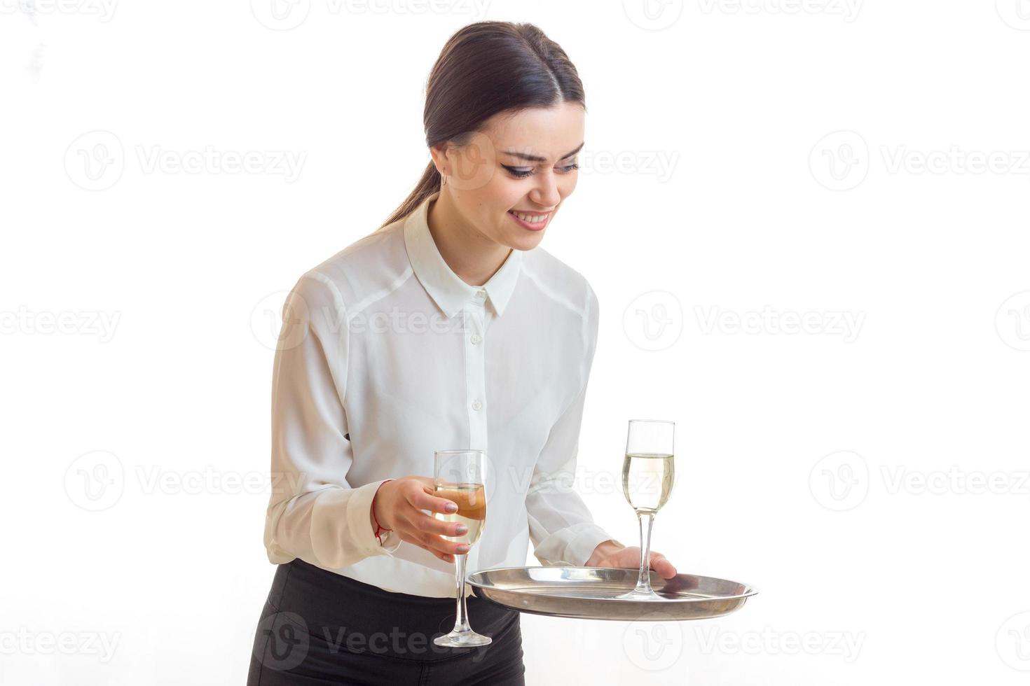 Cheerful young waitress with glasses of wine on a trey smiles photo