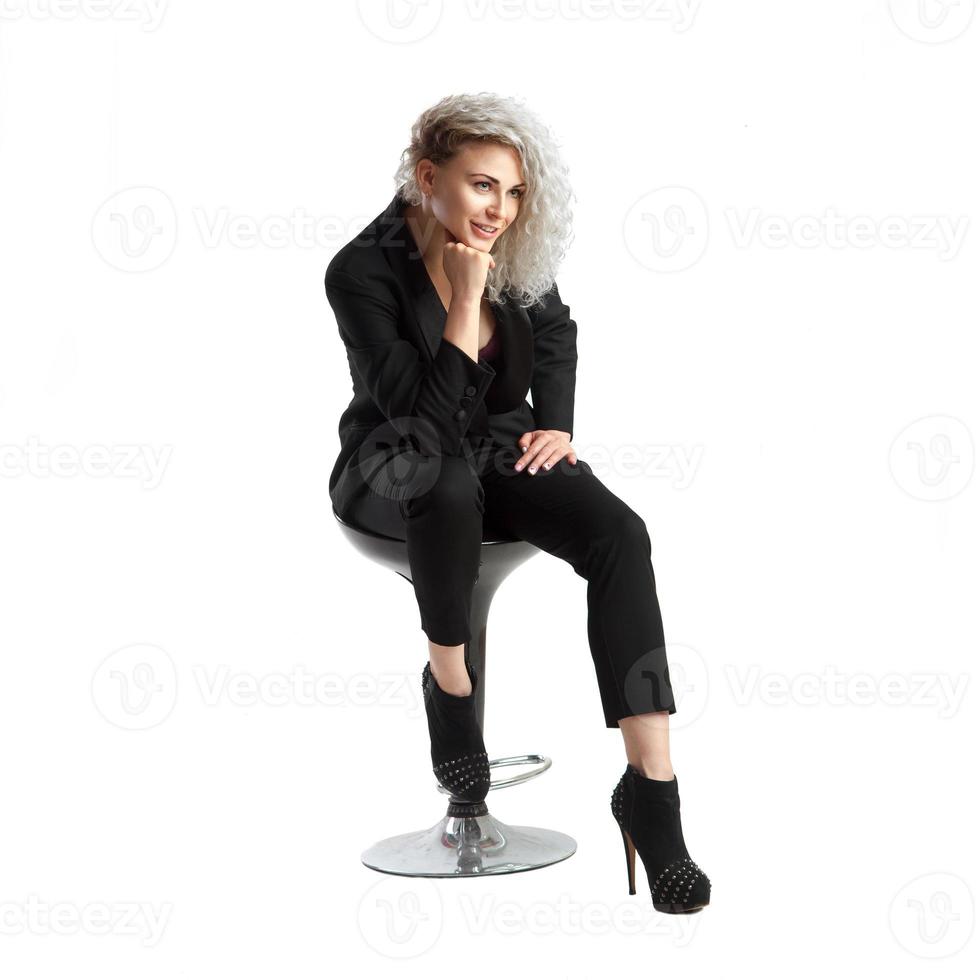 Blonde woman with curly hair sits in chair photo