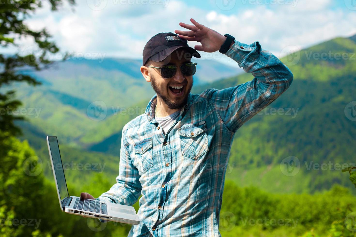 young man in sunglasses and with a laptop in hand photo