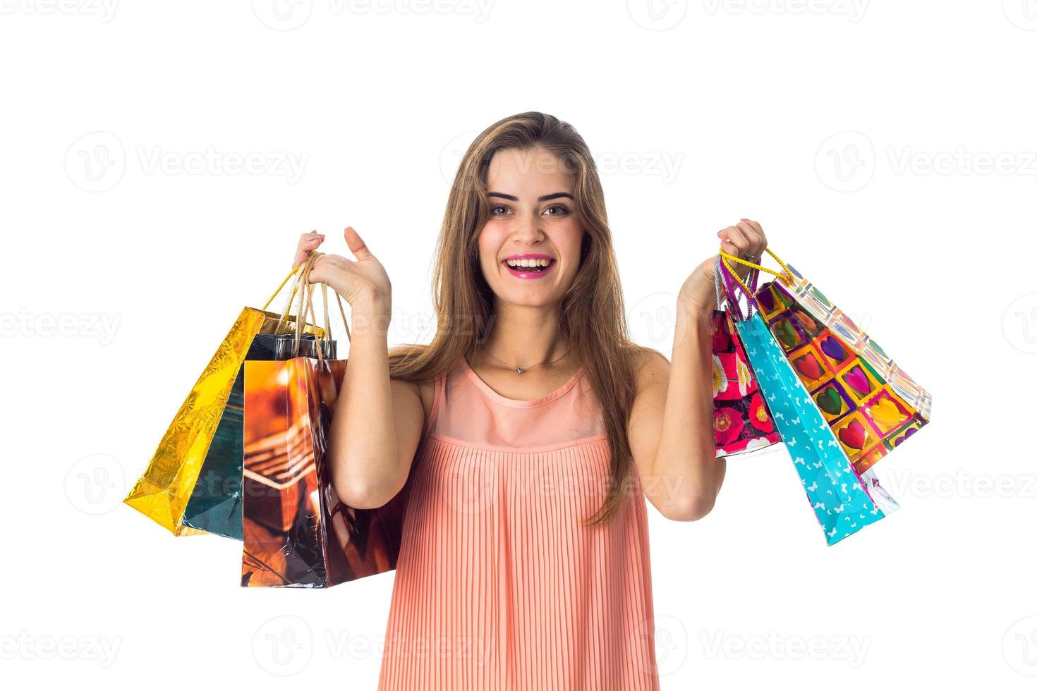 fun pretty girl looks straight and keeps two hands many colored packages isolated on white background photo