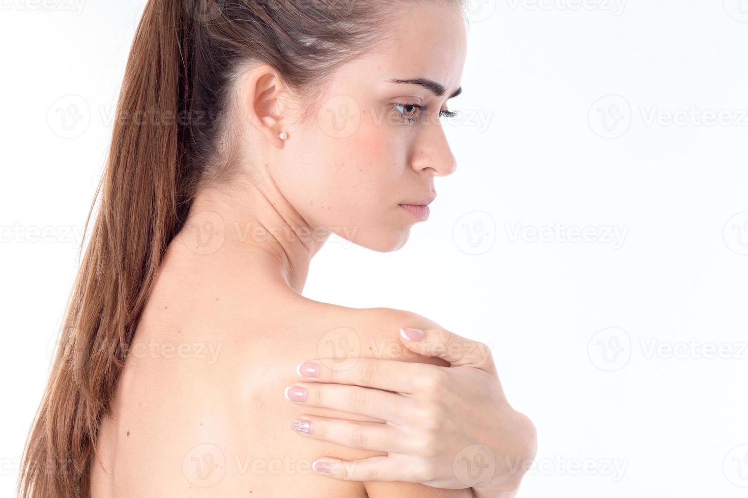 young girl turned sideways and keeps hand shoulders photo