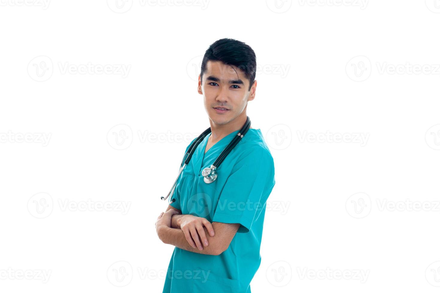 young handsome man doctor posing in uniform isolated on white background in studio photo