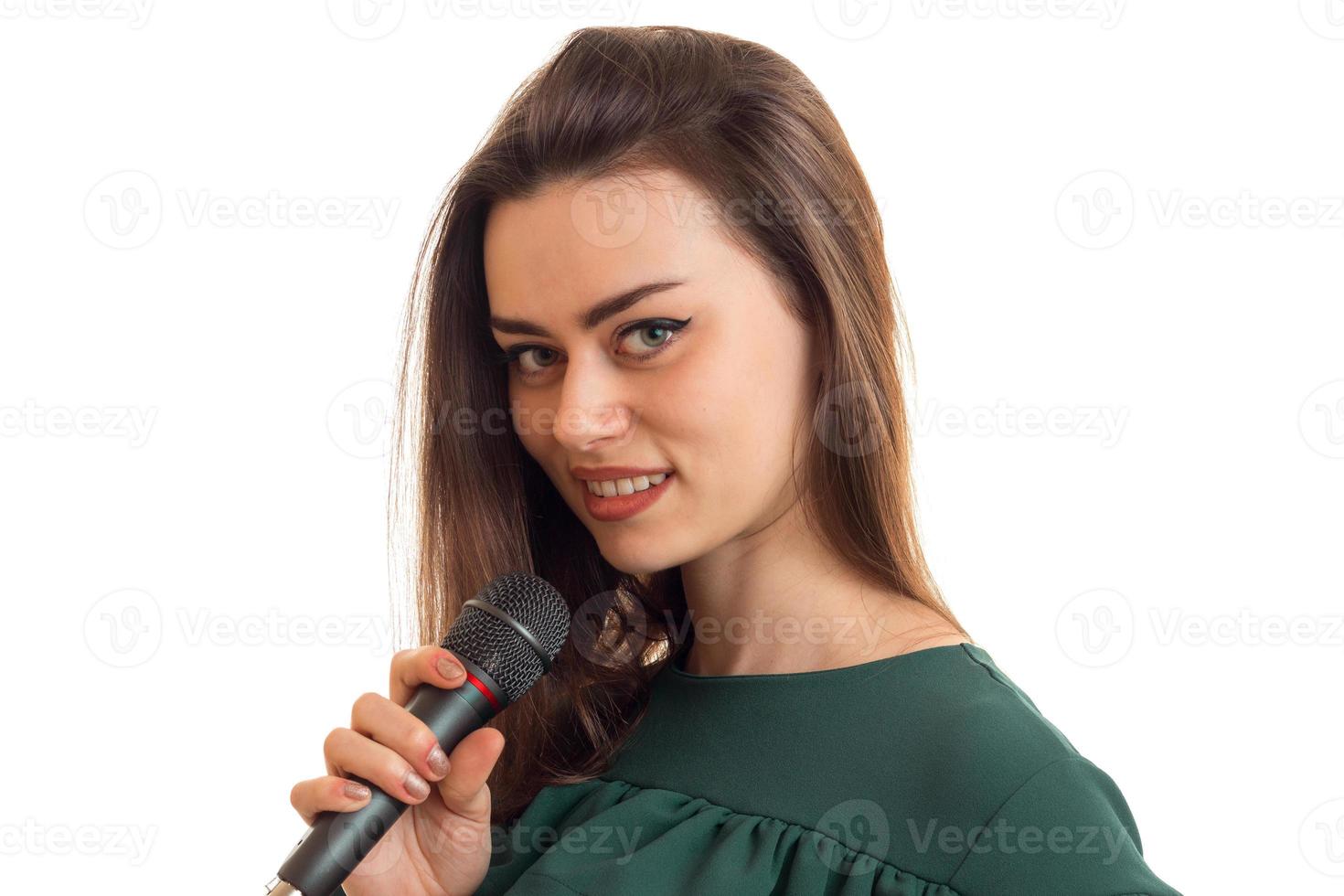 Cheerful young girl smiling on camera with microphone in hands photo