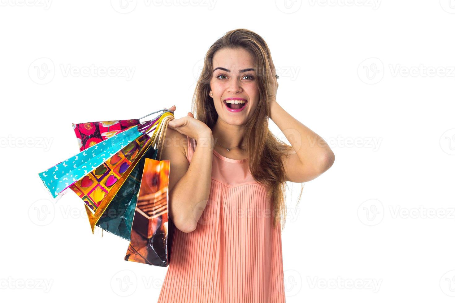 una chica feliz mantiene la pelota detrás de la cabeza y, por otro lado, muchos paquetes están aislados en un fondo blanco foto