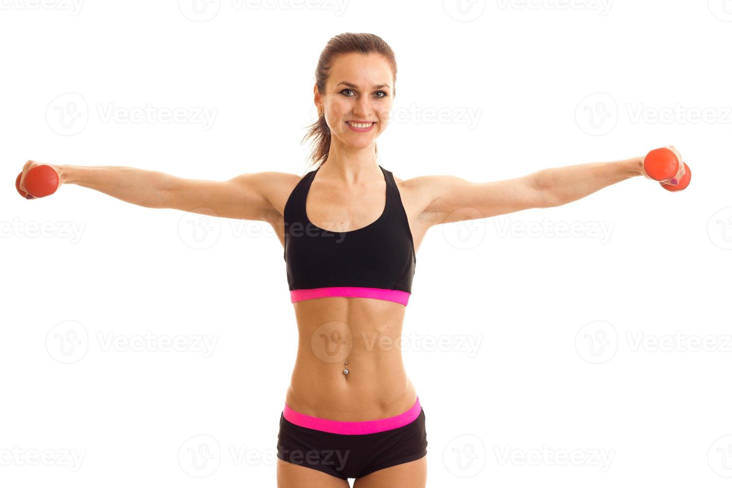 young beautiful girl smiling keeps hands at the sides with dumbbells and looking forward photo