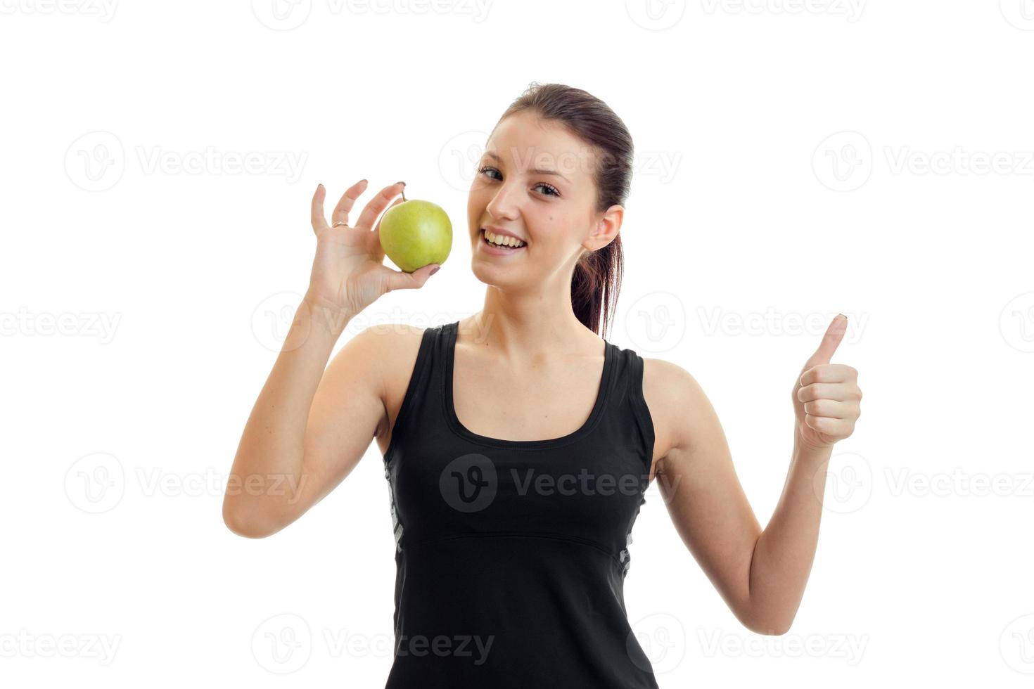 horizontal portrait of young slim girl in a black t-shirt who holds in her hand a Green Apple and shows class photo
