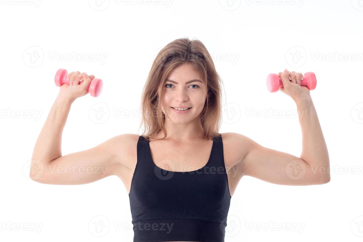 sports girl smiling and clenching his two arms with dumbbells photo