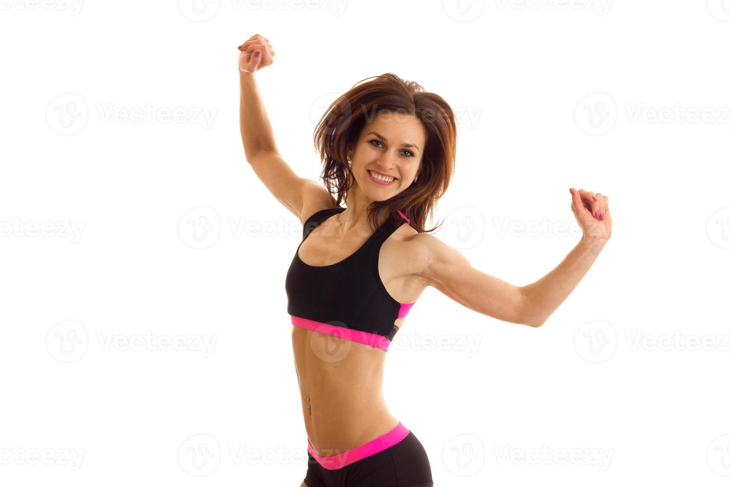 a cheerful athletic girl in top jumps up raises her hands and laughs photo