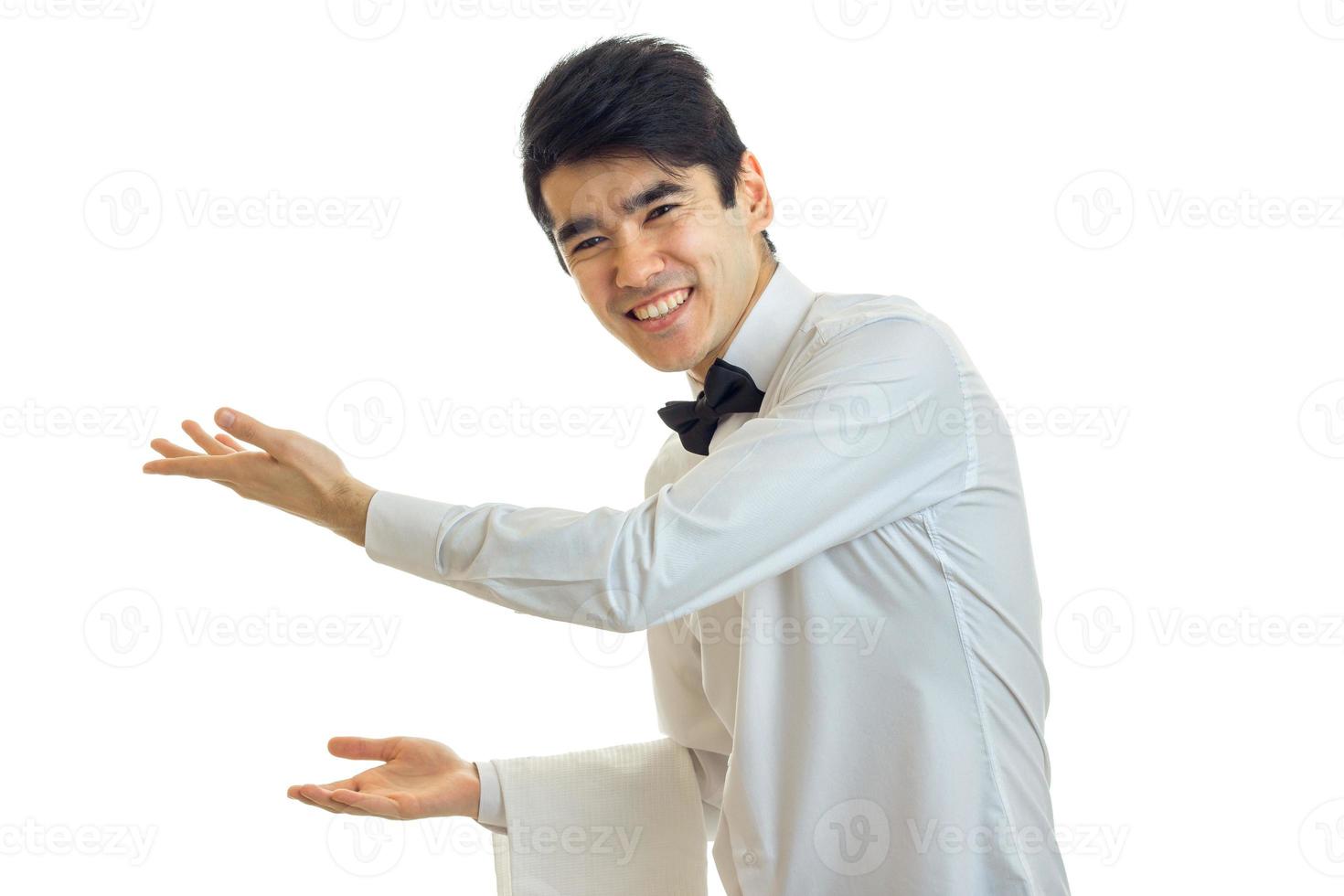 joyful handsome waiter reaches out his hands forward and invites people photo