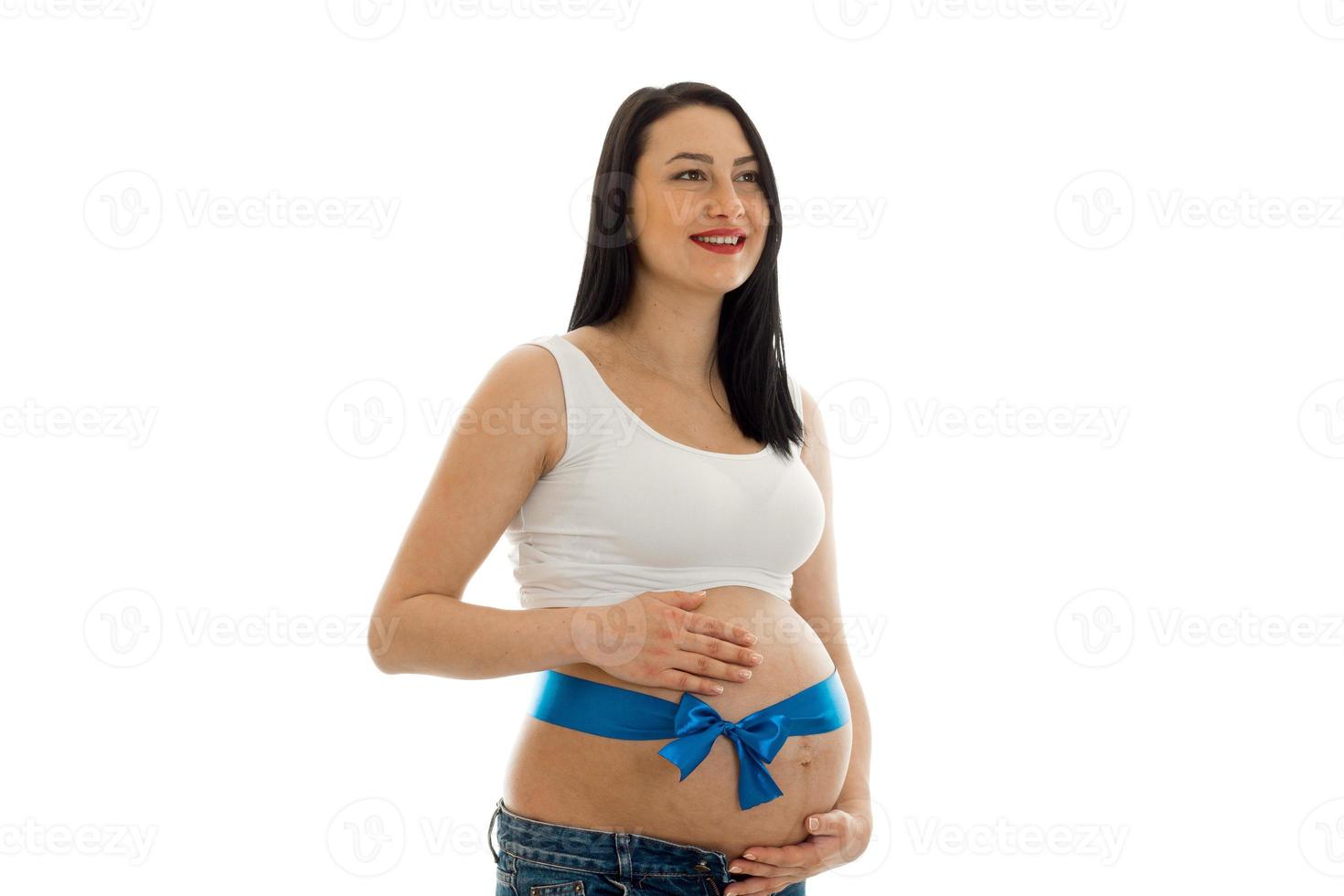 cheerful pregnant brunette woman posing with blue tape on her belly isolated on white background photo