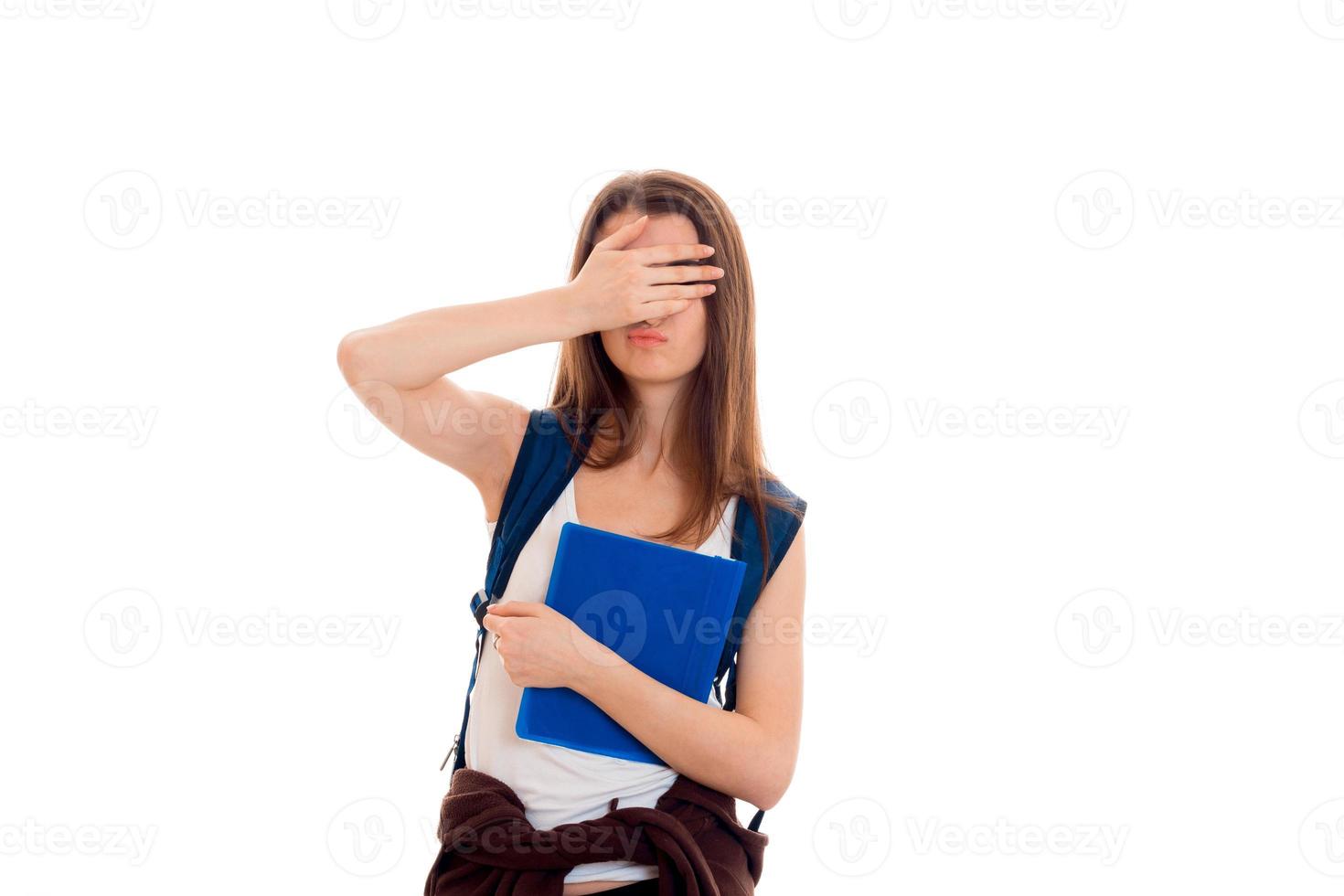 joven estudiante morena con mochila azul y un montón de libros en las manos posando y mirando a la cámara aislada de fondo blanco foto