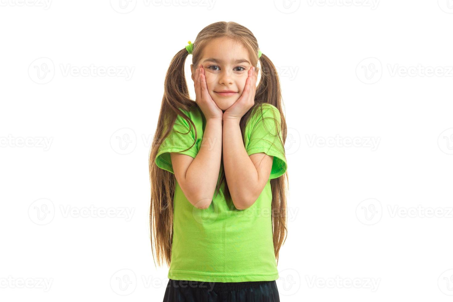 cute little girl in the green shirt looks and smiles at the camera photo