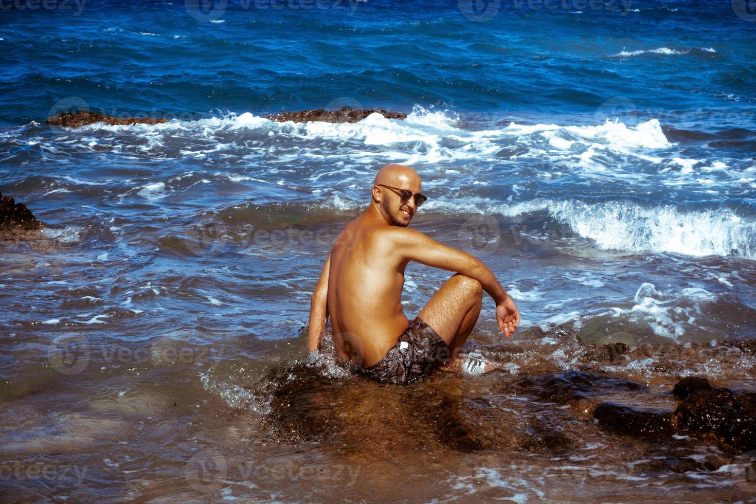 young tanned guy on the Rocky seashore photo