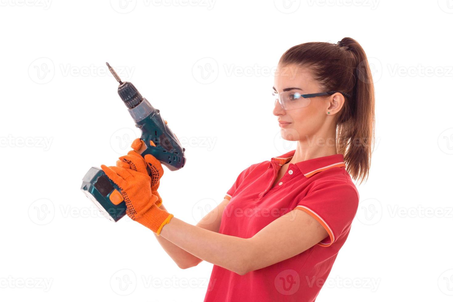 pretty brunette lady makes refurbish an apartment with drill in hands isolated on white background in studio photo