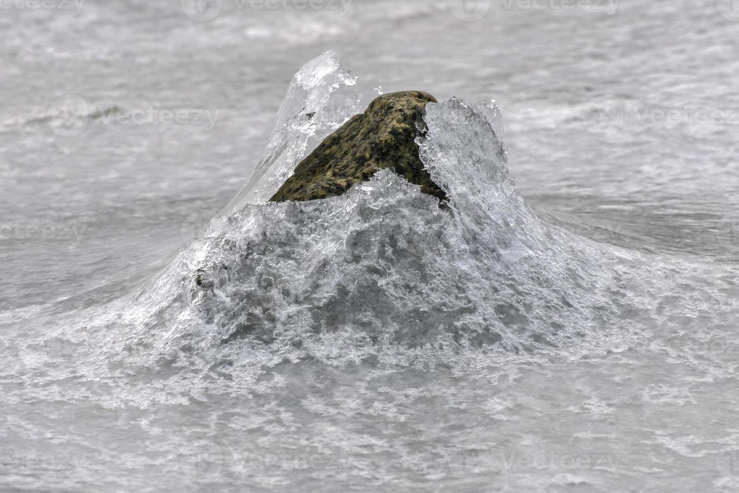 roca que se agrieta a través del hielo en vagspollen en las islas lofoten, noruega en el invierno. foto