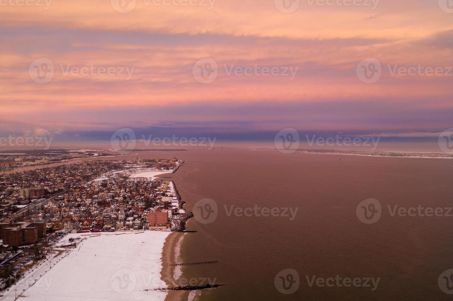 vista aérea de una playa de coney island cubierta de nieve durante el invierno al atardecer en brooklyn, nueva york foto