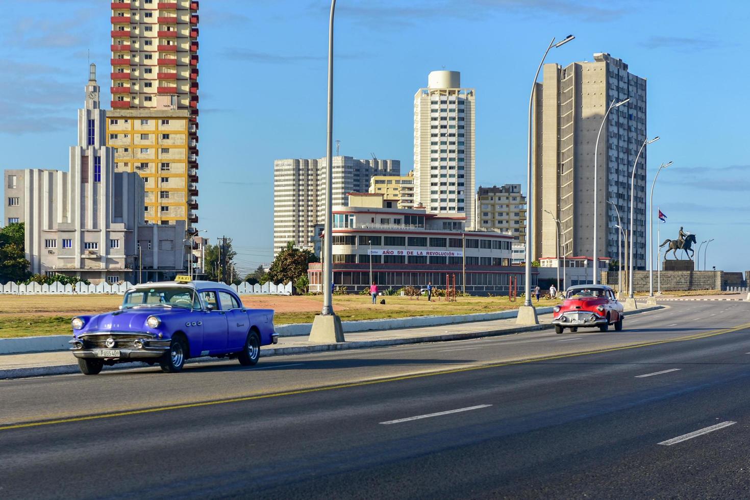 Havana, Cuba - Jan 15, 2017 -  Classic car driving along the Malecon with the Casa de las Americas in the background in Havana, Cuba. photo